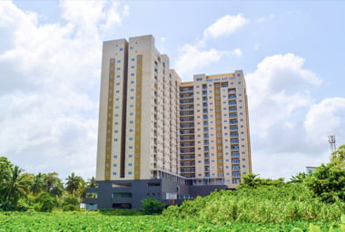 beige-apartment-building-amidst-greenery-with-blue-sky-above